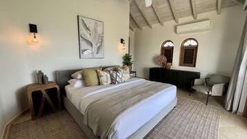 Un dormitorio con cama, mesita de noche, luz empotrada, ventilador de techo, obra de arte y vistas al exterior.