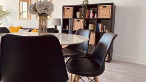 A dining area with a round table, black chairs, and a vase of flowers. - Spacious 2 Bedroom City pad in Old Street London (London)