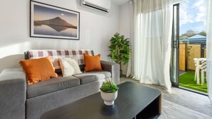 Una sala de estar moderna con un sofá gris, una mesa de centro negra y una planta.