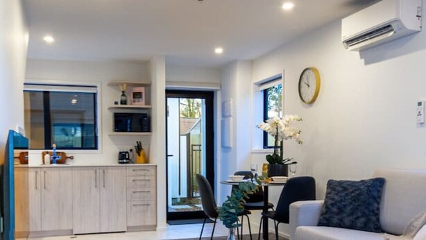 Un salon moderne comprenant un canapé, une table basse et un coin repas avec des chaises.