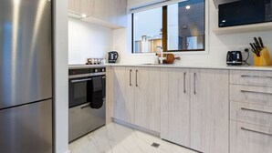 Une cuisine moderne dotée d’appareils électroménagers en acier inoxydable, de meubles de rangement en bois clair et d’une grande fenêtre qui laisse entrer la lumière naturelle.