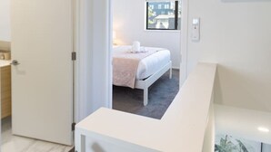 A modern hotel room with a bed, a bathroom, and a staircase.