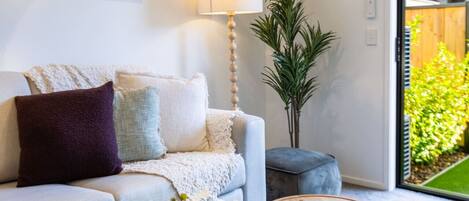 A modern living room with a sofa, a round coffee table, a floor lamp, and a potted plant.