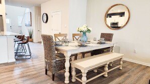 A dining area with a wooden table, chairs, a vase of flowers, and a mirror on the wall. - 3 Pools + Gameroom & Beach Shuttle Near Bethany Beach! (Millville)