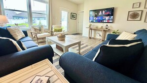 A living room with a large TV, two sofas, a coffee table, and a chair. - 3 Pools + Gameroom & Beach Shuttle Near Bethany Beach! (Millville)