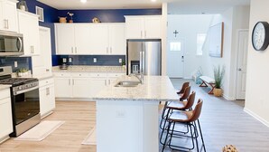 A modern kitchen with white cabinets, stainless steel appliances, and a granite countertop. - 3 Pools + Gameroom & Beach Shuttle Near Bethany Beach! (Millville)