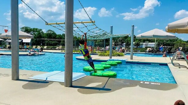 A pool area with a climbing net structure and green floating mats. - 3 Pools + Gameroom & Beach Shuttle Near Bethany Beach! (Millville)