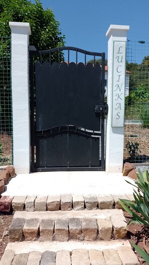 Ein schwarzes Tor mit einem Schild, auf dem 'LUCINAS' steht, in einem Garten.