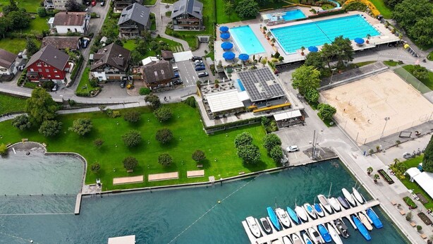 Luchtbeeld van een woonwijk met huizen, een zwembad en een jachthaven met boten.