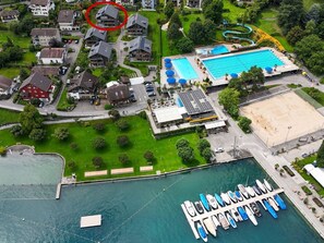 Vue aérienne d’un quartier résidentiel avec des maisons, une piscine et un port de plaisance où sont amarrés des bateaux.
