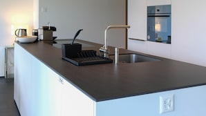 Een moderne keuken met een ingebouwd eiland, roestvrijstalen apparatuur en een strakke kraan.