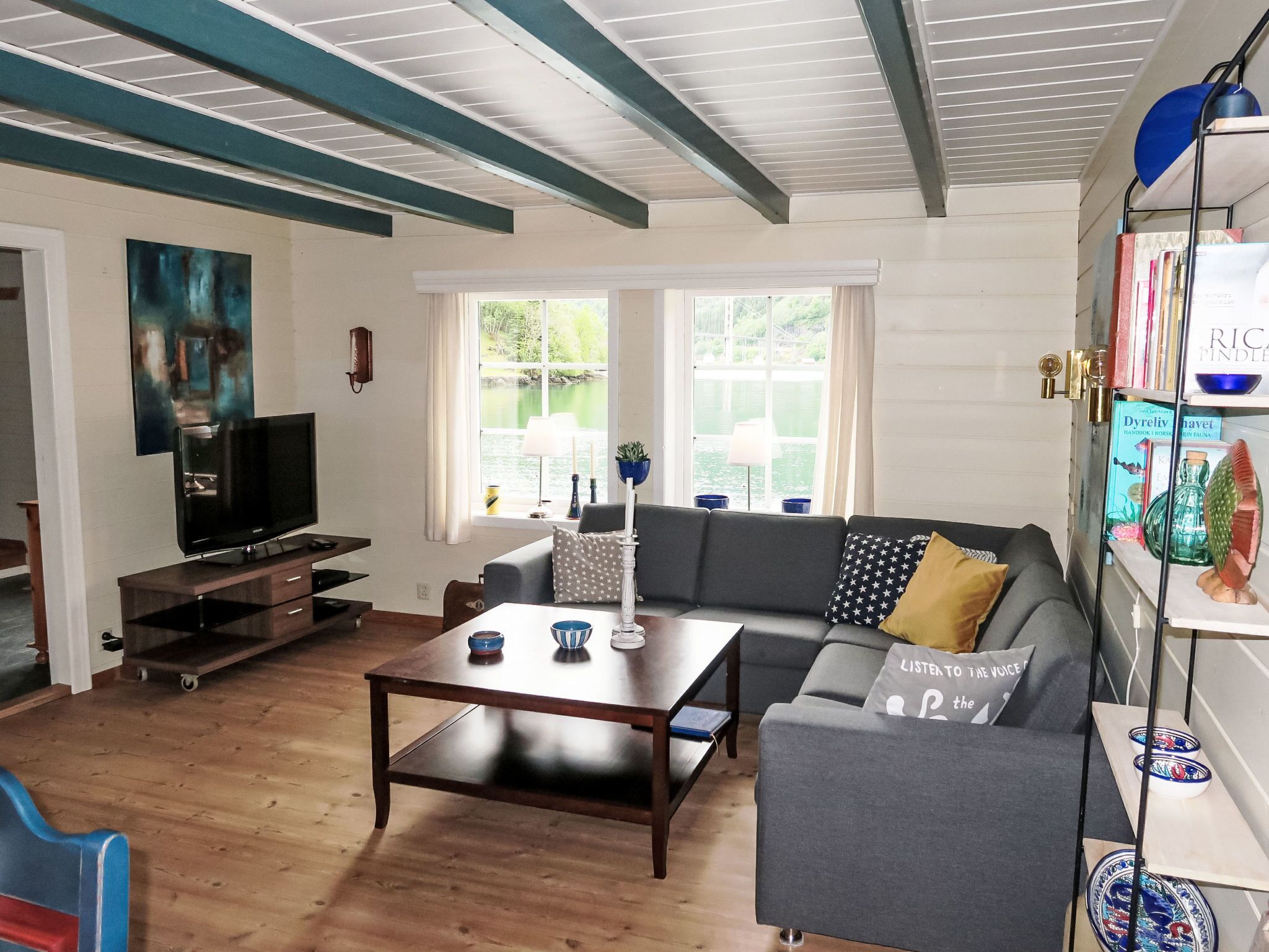A living room with a TV, sofa, coffee table, and a bookshelf.