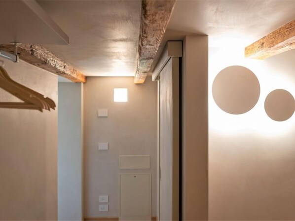 A hallway with exposed wooden beams, a door, and a wall-mounted light fixture with two circular shapes.