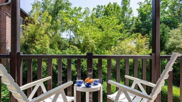 A covered outdoor area with two white chairs and a small table with a blue bowl and a cup. - Pavillon Gabriel by Interhome (Deauville-Trouville)