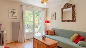 A living room with a wooden coffee table, a green sofa with red cushions, a red lamp, and a large mirror on the wall. - Pavillon Gabriel by Interhome (Deauville-Trouville)
