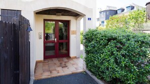 A building entrance with a red door, a black gate, and a tiled pathway leading to the entrance. - Pavillon Gabriel by Interhome (Deauville-Trouville)