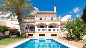 Un grand bâtiment à deux étages, avec une piscine devant.