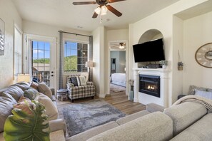 Amplia sala de estar con chimenea, televisor montado arriba y un gran ventanal con vistas al exterior.