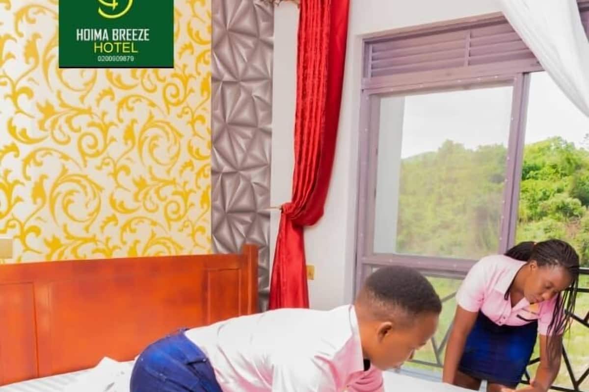 Une chambre d’hôtel avec un lit, une fenêtre avec des rideaux et un mur décoré de motifs.