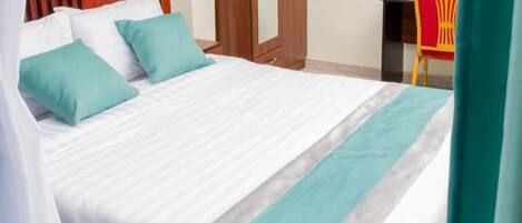 Quarto de hotel com cama, guarda-roupa, escrivaninha e televisão.
