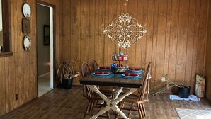 Een eetruimte met een houten tafel en stoelen, een plafondventilator en een decoratief wandobject.
