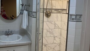 Een badkamer met een douchecabine, een wastafel, een spiegel en een handdoekhouder.