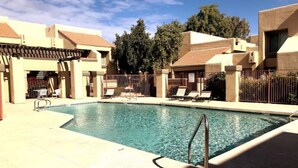 A swimming pool with lounge chairs and a pergola.