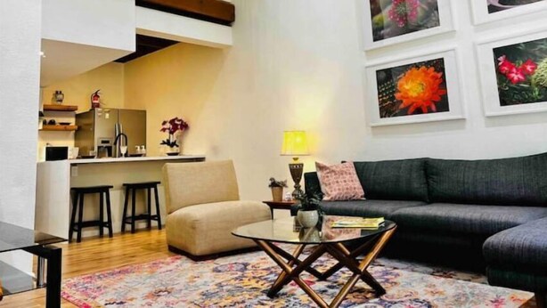 A living room with a sofa, a coffee table, and a kitchen in the background.