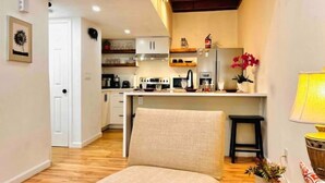 A compact living space with a kitchenette, a dining area, and a seating area with a sofa and a small table.