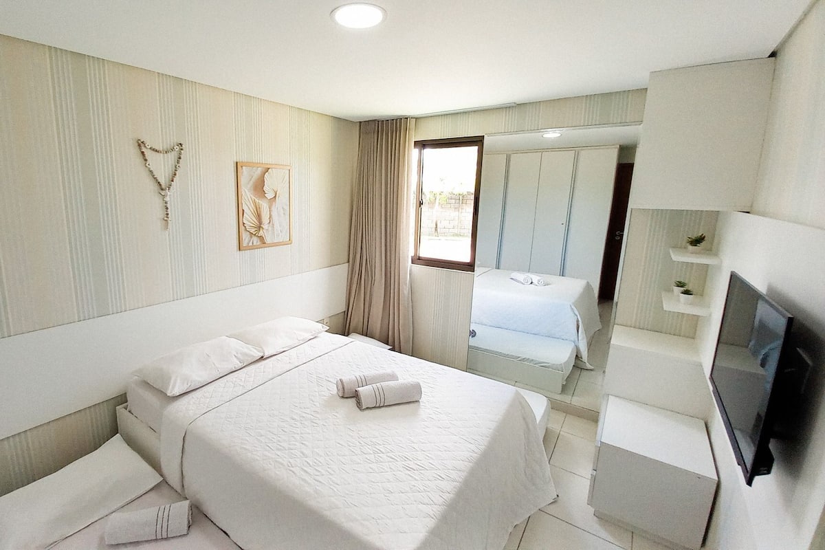 Ein Hotelzimmer mit Bett, Fernseher, Badezimmer mit Dusche und Spiegel.