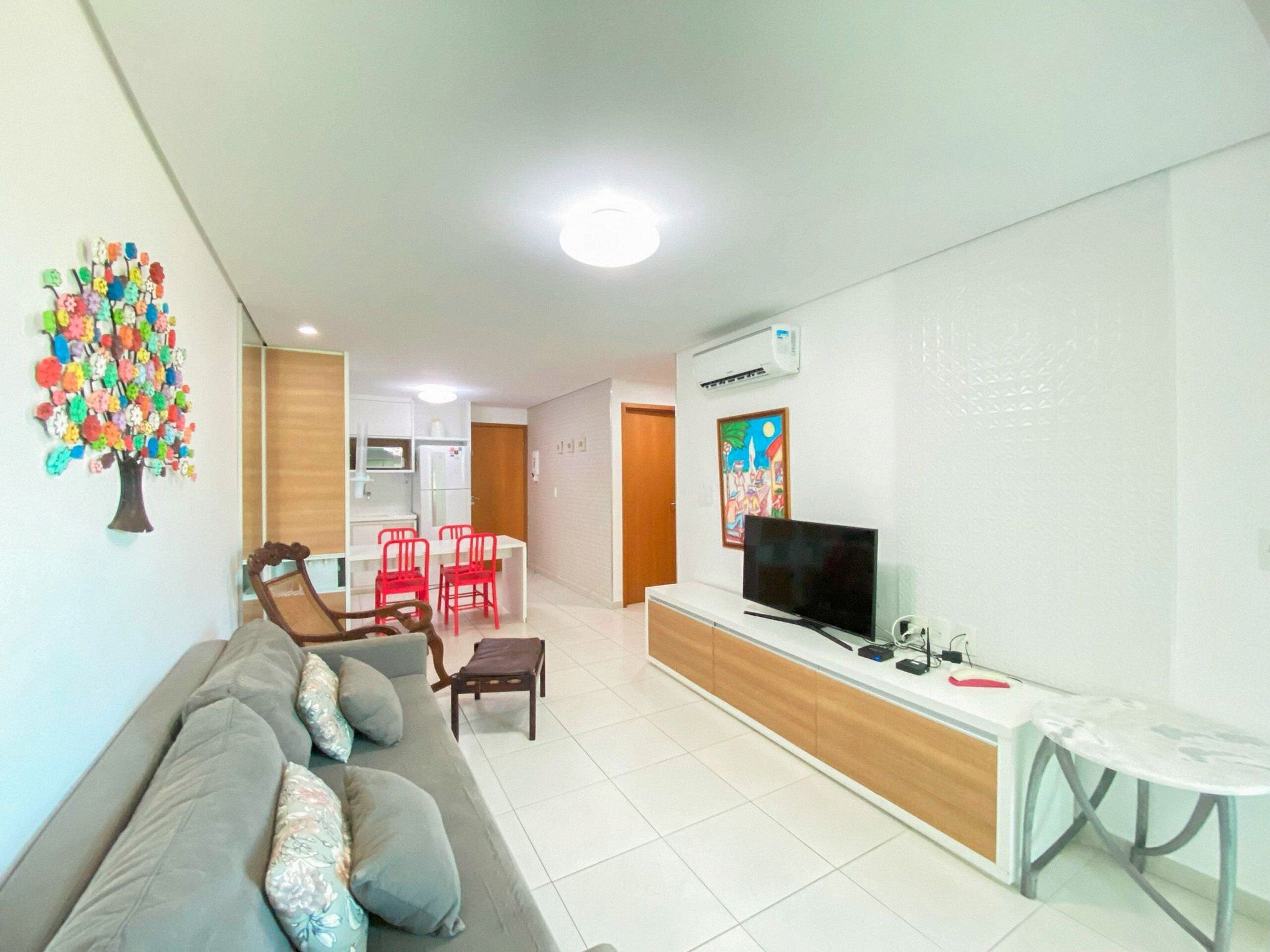 A living room with a sofa, red chairs, a TV, and a small table.