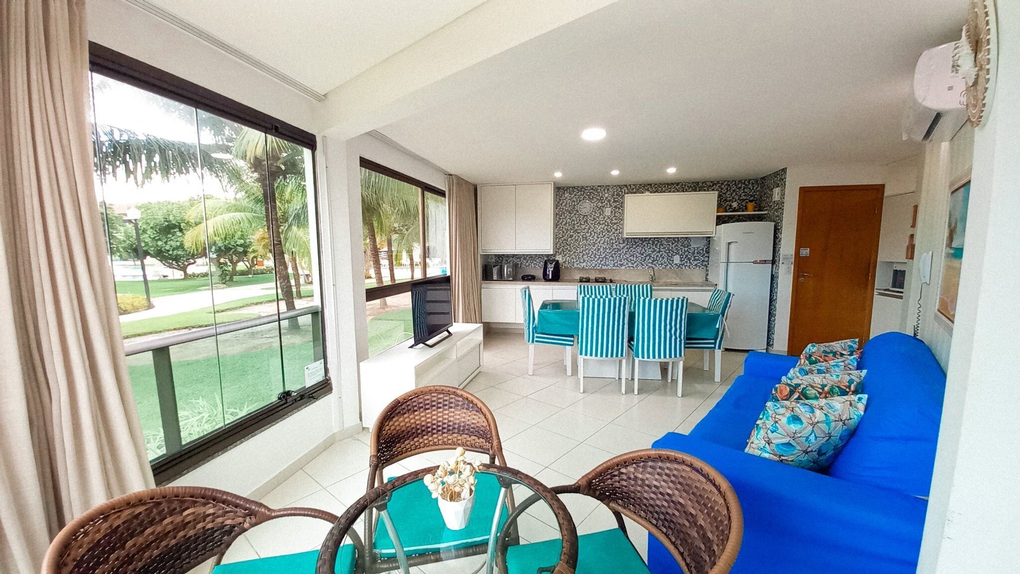 A modern apartment with a balcony, a dining area, a kitchen, and a living room with a sofa.