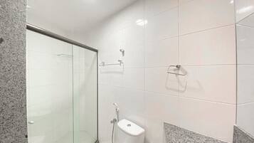 A modern bathroom with a glass shower enclosure, a toilet, and a granite countertop.