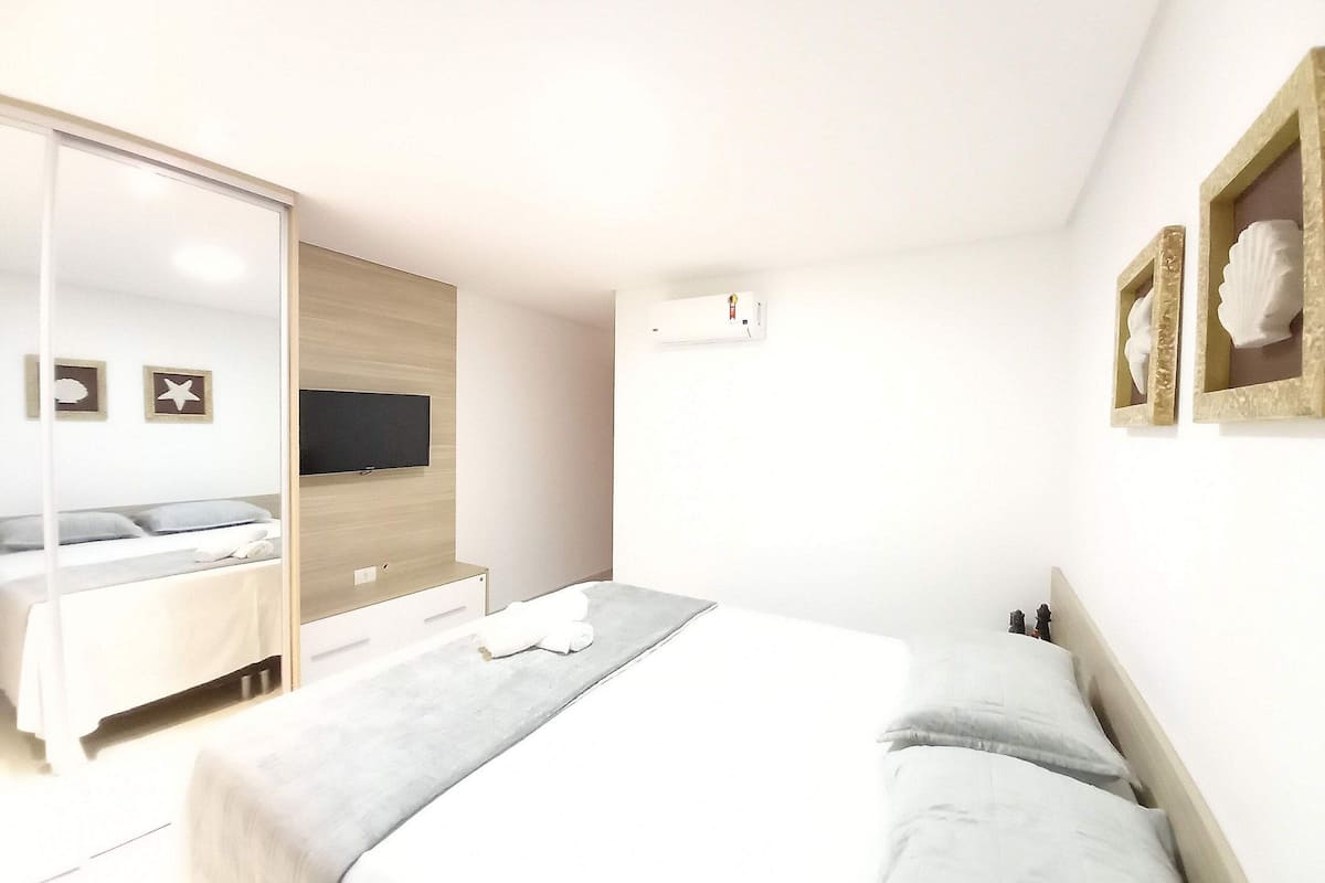 Ein Schlafzimmer mit Bett, Fernseher, Kleiderschrank und Spiegel.
