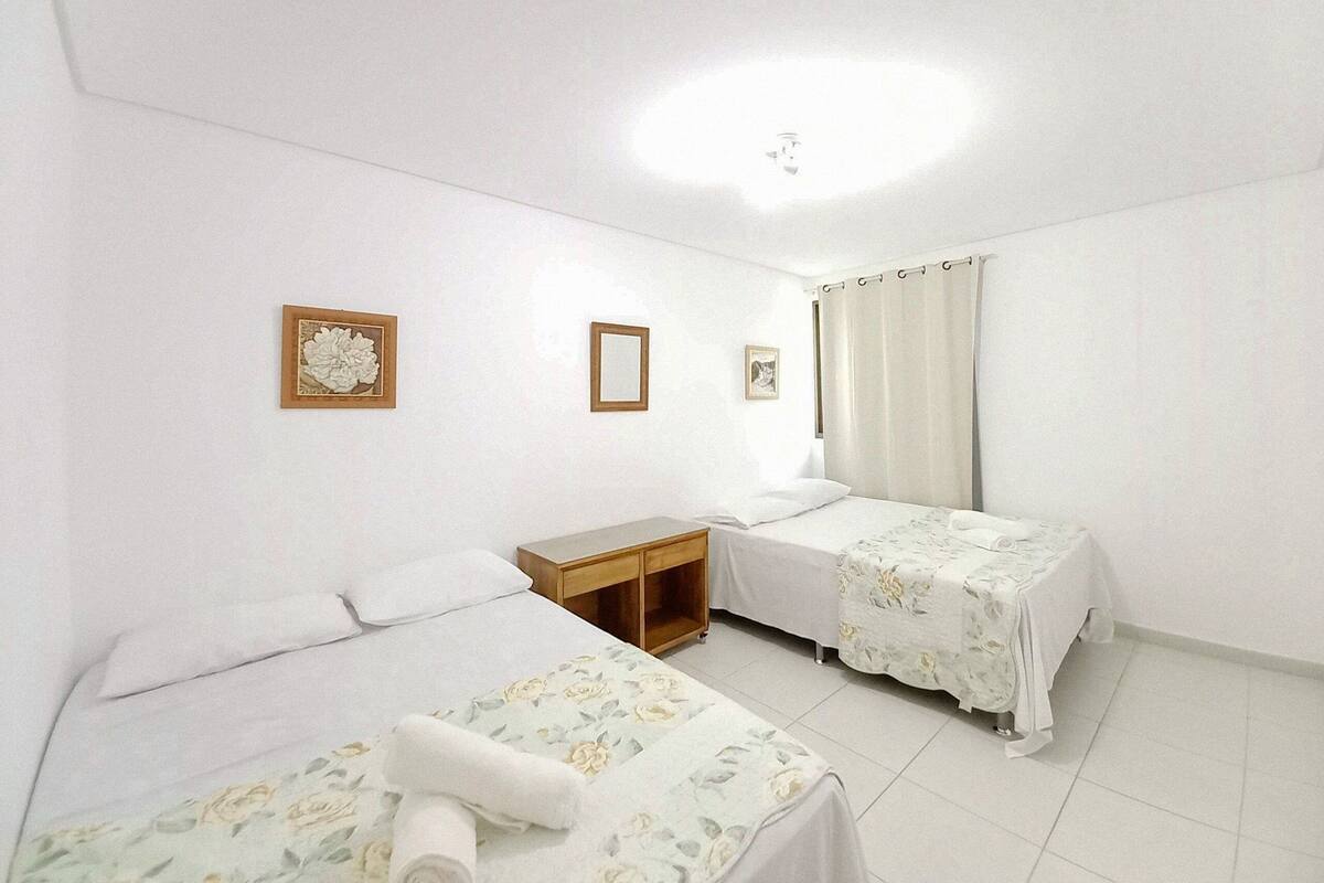 Ein Hotelzimmer mit zwei Betten, einem Holznachttisch, einem kleinen Tisch und einer Deckenleuchte.
