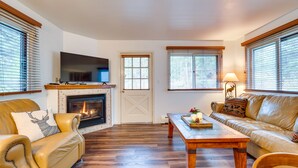 A living room with a fireplace, leather sofas, a wooden coffee table, and a television. - Estes Park Condo Rental: Balcony w/ River Views! (Estes Park)