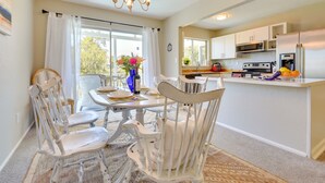 A dining area with a table, chairs, and a chandelier. There is a kitchen area with appliances and cabinets in the background. - Walk to Marina: Home w/ Pool in Palmetto (Palmetto)