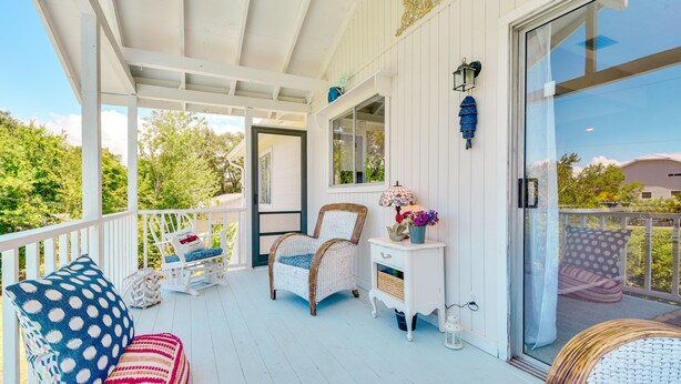 A covered porch with white railings, wicker furniture, and a white dresser with a mirror and lamp. - Walk to Marina: Home w/ Pool in Palmetto (Palmetto)