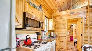 Ein Interieur einer Holzhütte mit einer Küche, die einen Herd, ein Backofen, eine Mikrowelle und einen Kühlschrank beinhaltet.