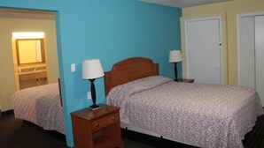 A hotel room with two beds, wooden nightstands with lamps, a mirror, and a door.