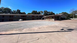 Un motel doté d’un parking et d’un petit bâtiment avec une véranda couverte.