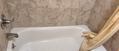Un baño con una bañera blanca, una toalla y una cortina de ducha.