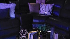 A living room with a black leather sofa, a round coffee table with a decorative vase, and a potted plant. - Cozy Luxury Midtown 1 Bedroom Condo  (Atlanta)