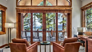 A cozy room with leather chairs, a desk, and large windows overlooking a deck with outdoor furniture. - 8 Sierra Shores - Stunning Lakefront 4BR/4BA (South Lake Tahoe)