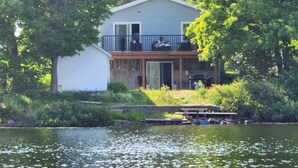 A house with a balcony overlooking a body of water, surrounded by trees. - Water front Getaway (Sault Ste. Marie)