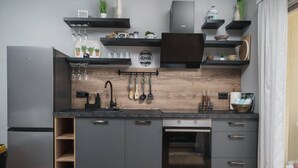 A modern kitchen with grey cabinetry, a built-in oven, and a stainless steel refrigerator.
