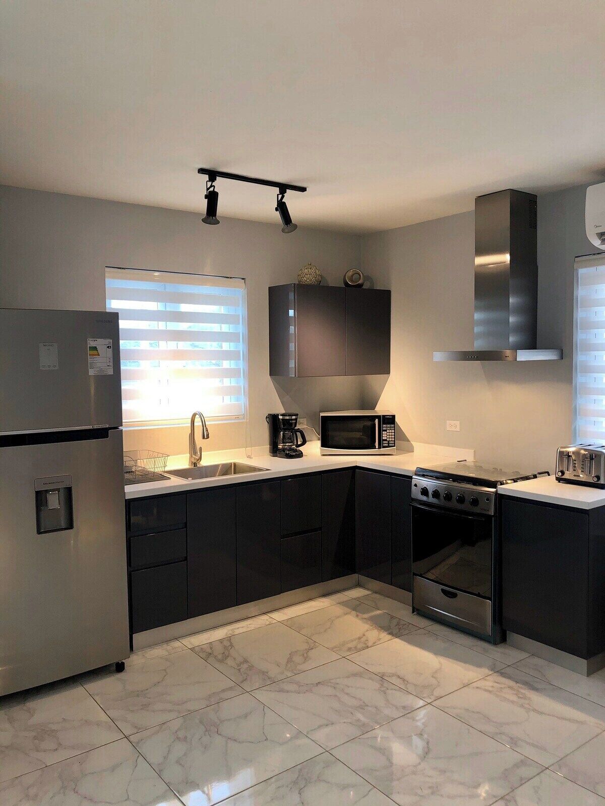 A modern kitchen with a stainless steel refrigerator, a microwave, a stove, and a toaster.