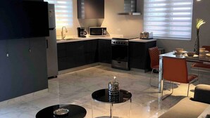 Cocina moderna con microondas, estufa y lavaplatos. Hay un comedor con mesa y sillas.