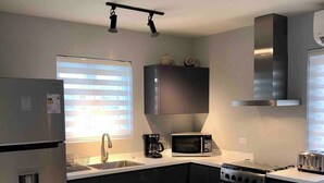 Una cocina moderna con un refrigerador de acero inoxidable, un microondas, una estufa y un tostador.