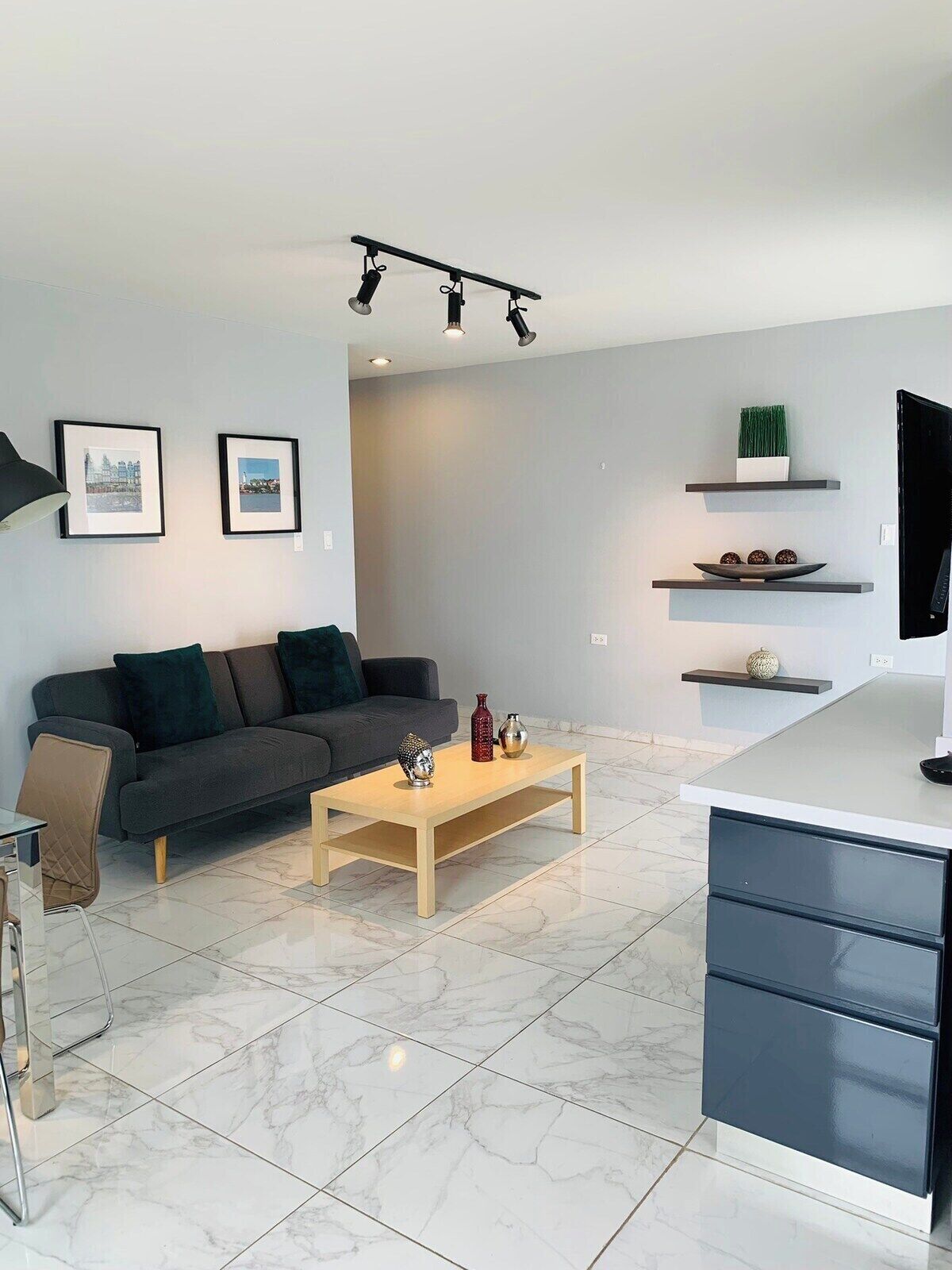 A modern living room with a sofa, coffee table, TV, and shelves.